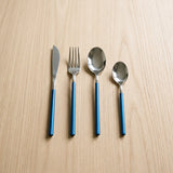 Germany Set — steel flatware with blue handles on a warm wood table