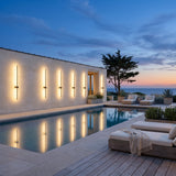 Luminous Line Outdoor Lights on a pool house wall, reflected in the water at dusk