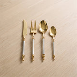 Noble Golden Cutlery Set — ornate gold flatware on a warm wood table