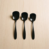 Singapore Serving Spoon — glossy black serving spoons on a warm wood table