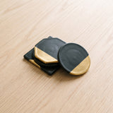 Onyx Coaster — black and gold drink coasters on a warm wood table