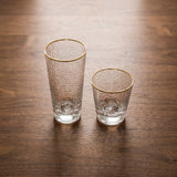 Class Glass — hammered gold-rim glass tumblers on a warm wood table