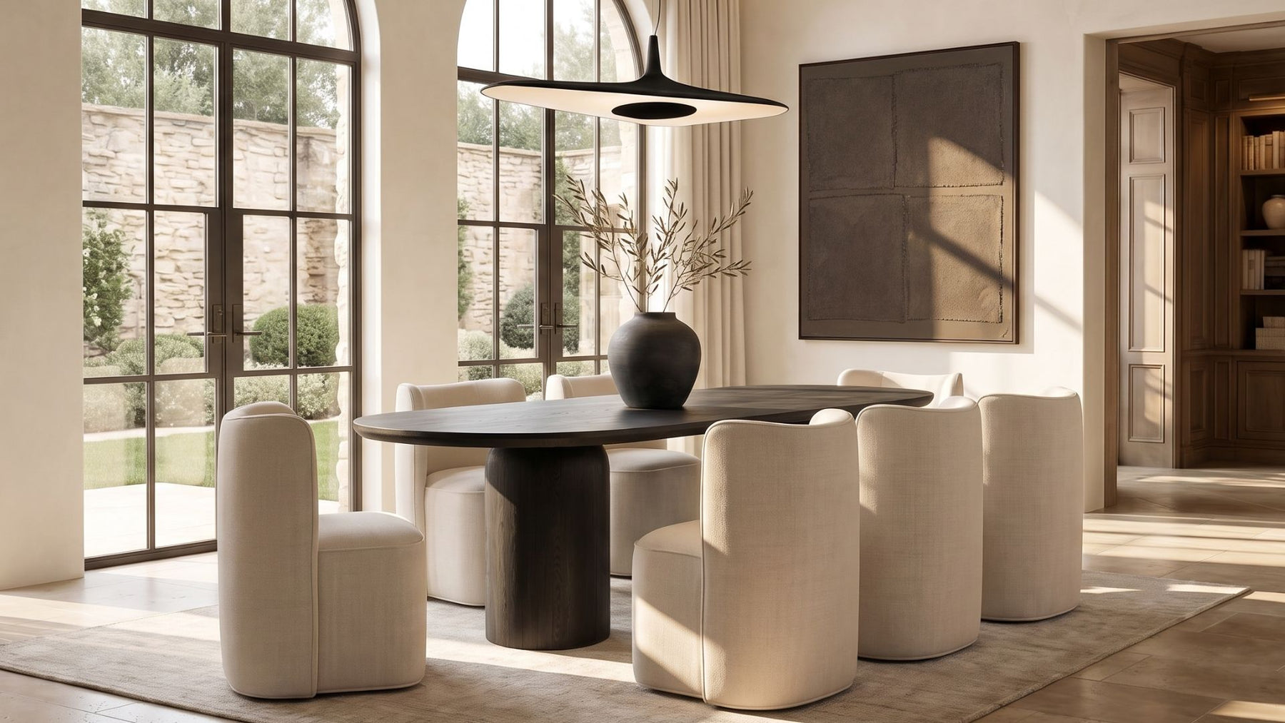 The Adler pedestal dining table in black oak, styled in a warm modern dining room